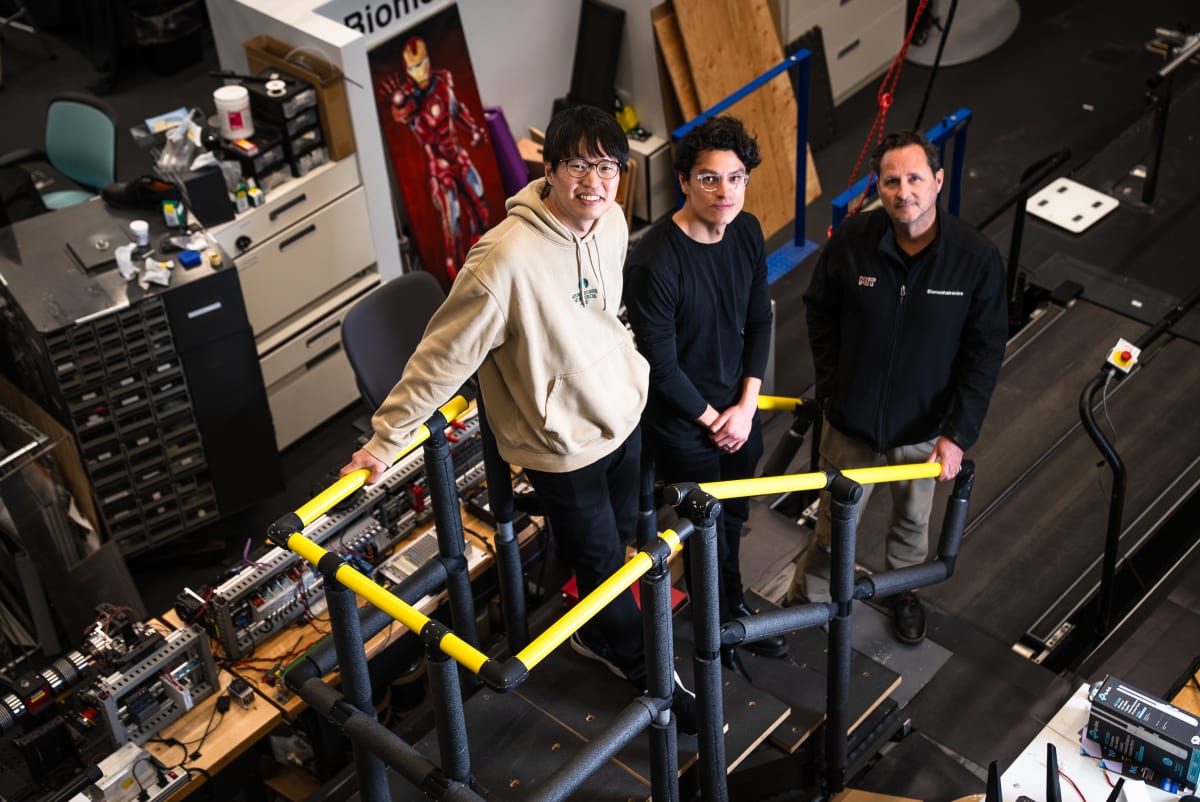 Three MIT researchers standing together in laboratory with equipment behind them