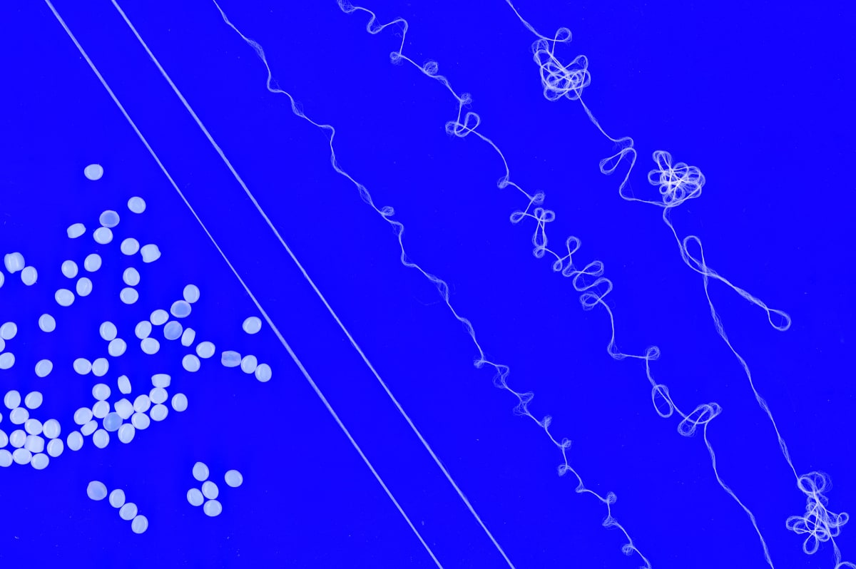 ** Hair-thin recyclable yarn fibers created from melted polyethylene resin pellets in laboratory process