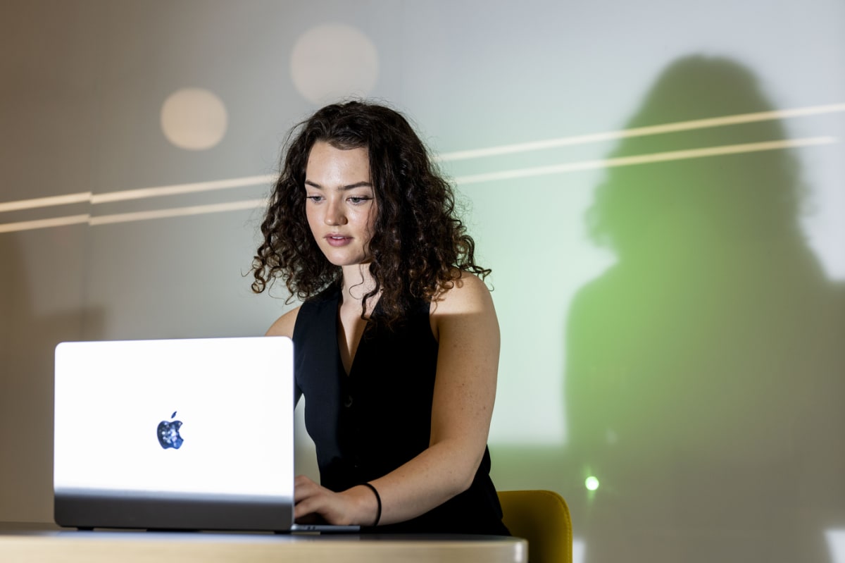 Young woman in professional attire stands confidently inside modern university research building