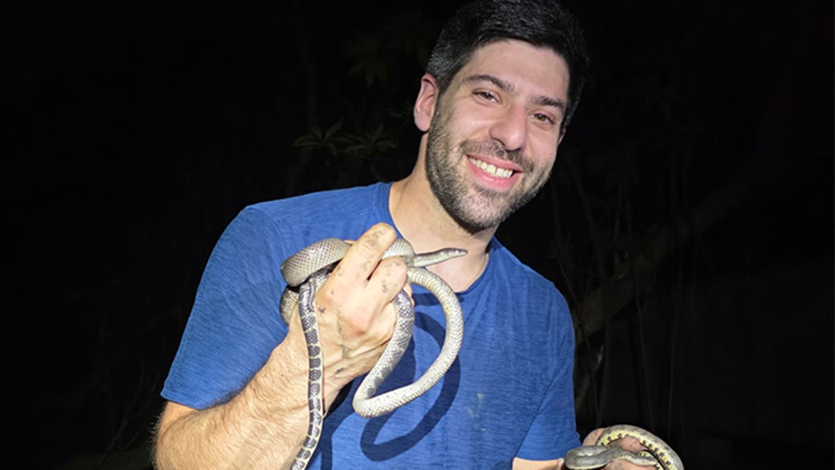 Biology professor Justin Bernstein holding a snake during field research in Thailand