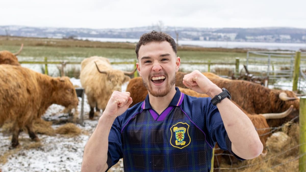Craig Ferguson walking along American highway with Scottish flag and backpack during cross-country mental health fundraising trek