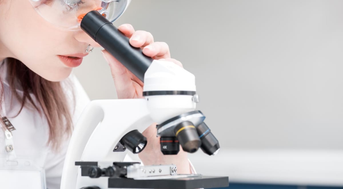 Female scientist working with microscope in modern research laboratory setting