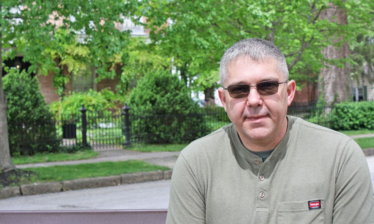 Smiling middle-aged man recovered from colon cancer standing confidently in casual clothing