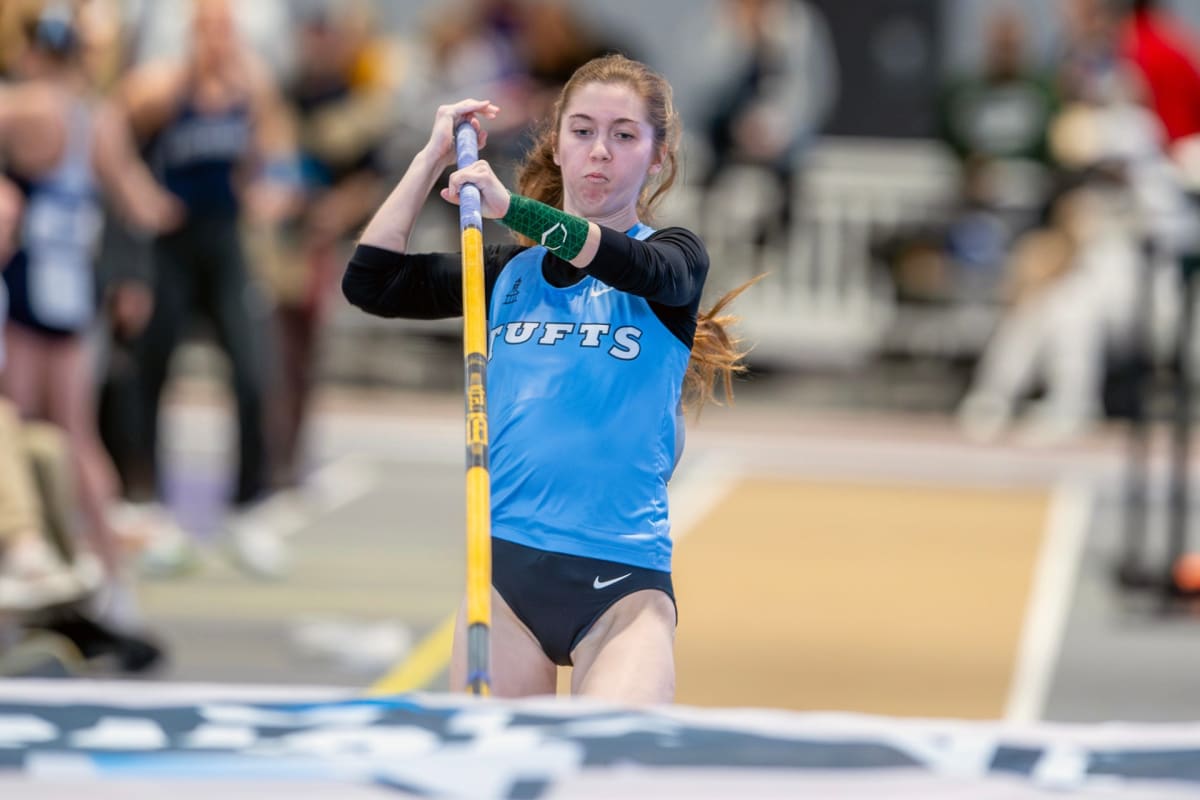 Sarah Firth pole vaulting during NCAA competition wearing Tufts University track and field uniform