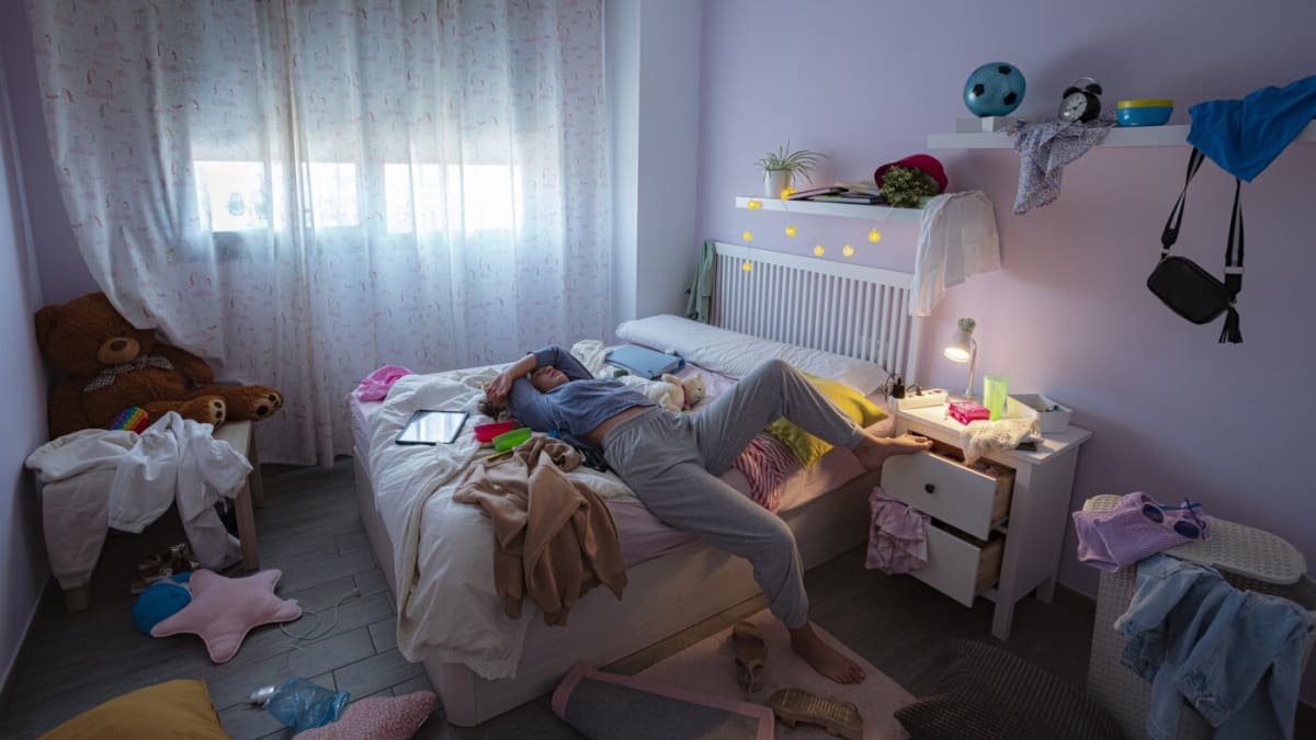 Tired teenage student resting head on desk near window in morning light