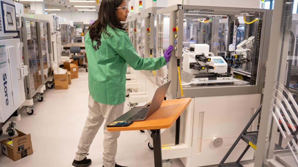 One-armed pipetting robot enclosed in glass performing automated laboratory experiments at Ginkgo Bioworks facility