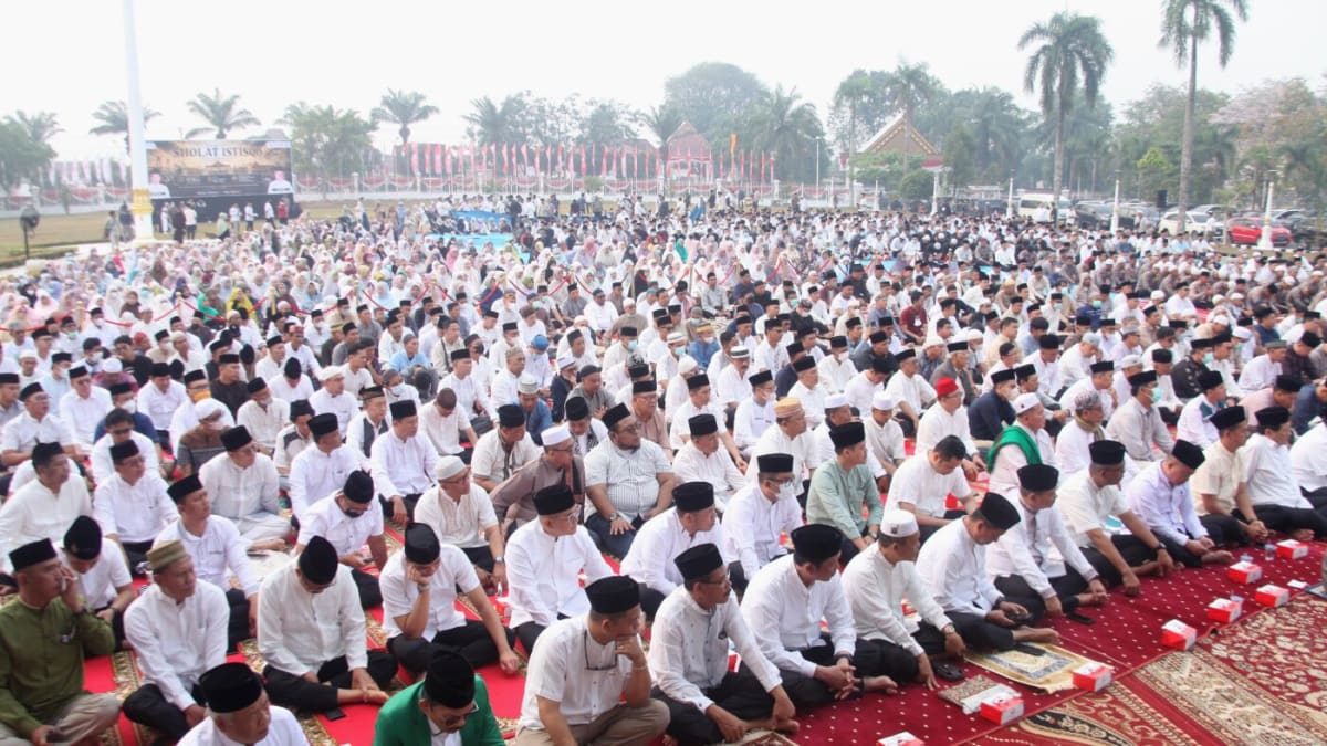 Three thousand Indonesian residents praying together in smoky courtyard during wildfire crisis response