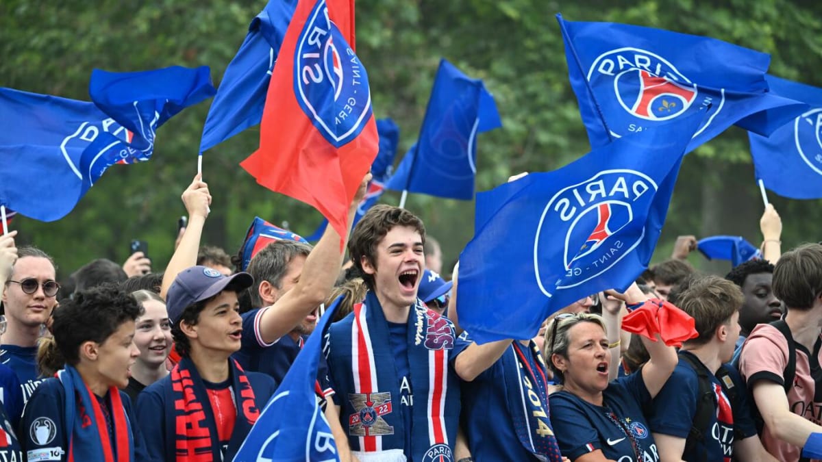 PSG supporters celebrating peacefully near Eiffel Tower with team trophy on stage