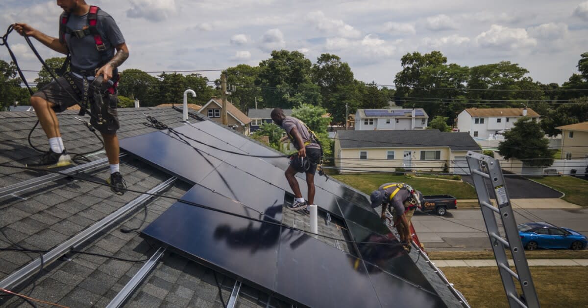 Solar panel installation workers on residential rooftop securing clean energy equipment