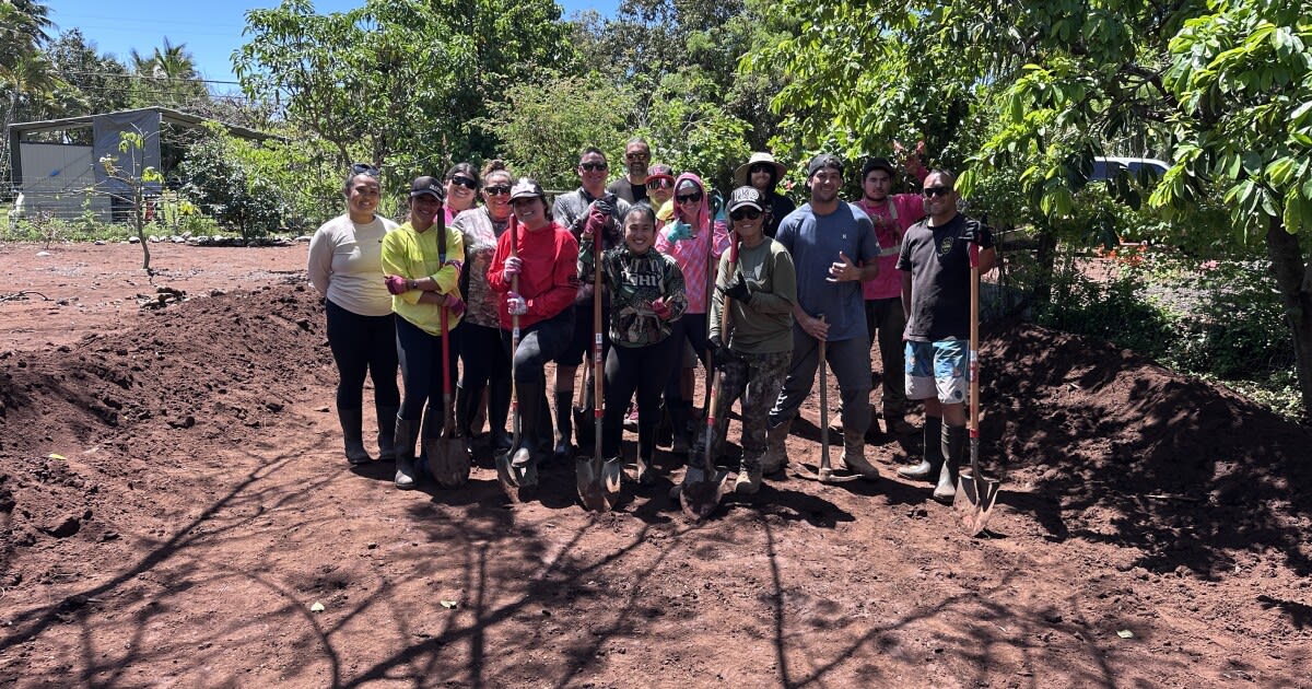Volunteers in work clothes shoveling mud from flooded property on Moloka'i island Hawaii