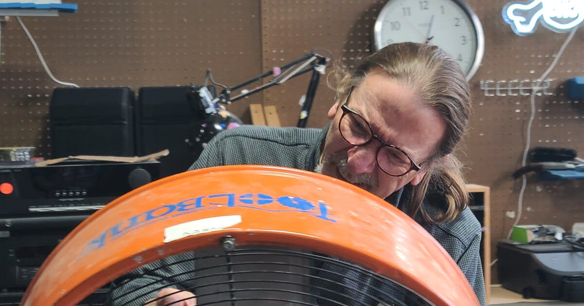 Retired engineer Mike Conaway repairs an old orange fan at Cincinnati Recycling and Reuse Hub