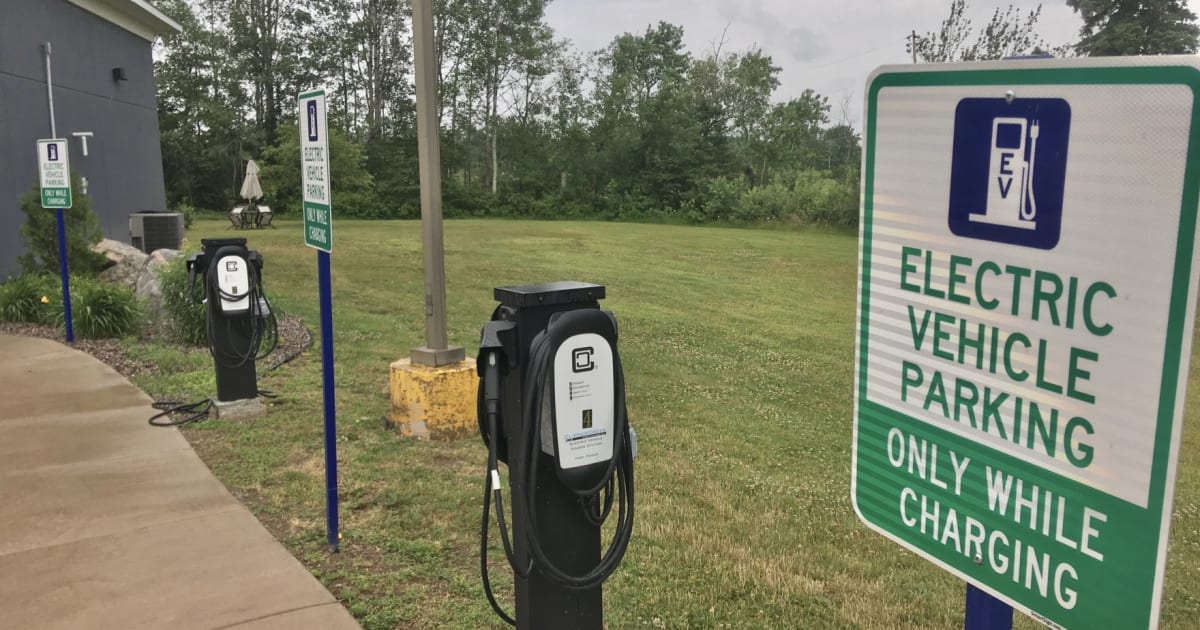 Electric vehicle charging at a station in Ann Arbor, Michigan with city buildings in background
