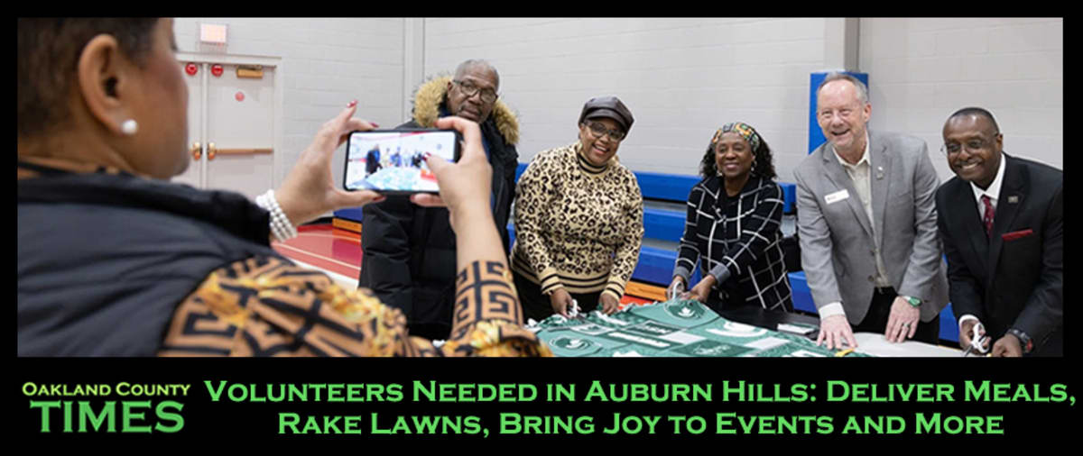 Volunteers raking colorful fall leaves in yard helping Auburn Hills community members in need