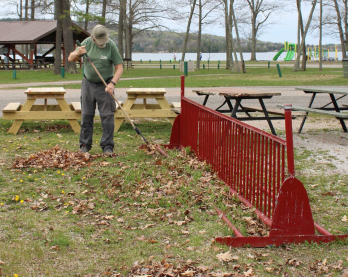 Volunteer raking leaves and debris at Lake Antoine Park during community cleanup day