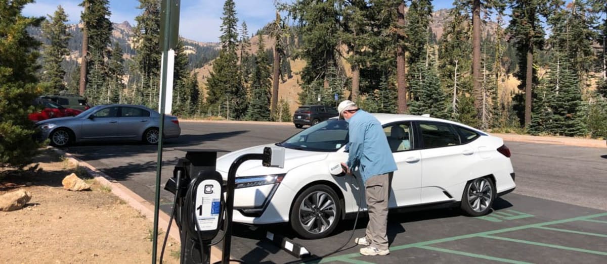 Electric vehicle charging at public station in Oregon with green landscape background