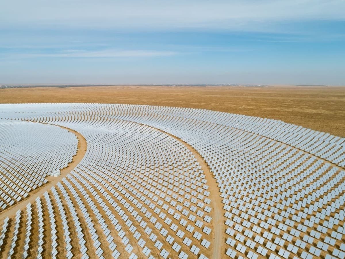 Solar panels stretching across California landscape under bright blue sky with battery storage facilities