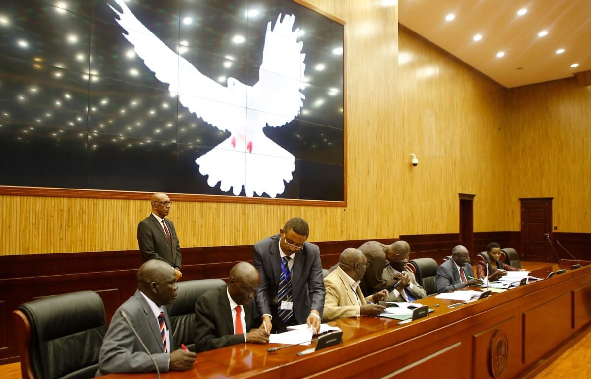 Delegates signing a peace agreement at a formal negotiation table in an international conference setting