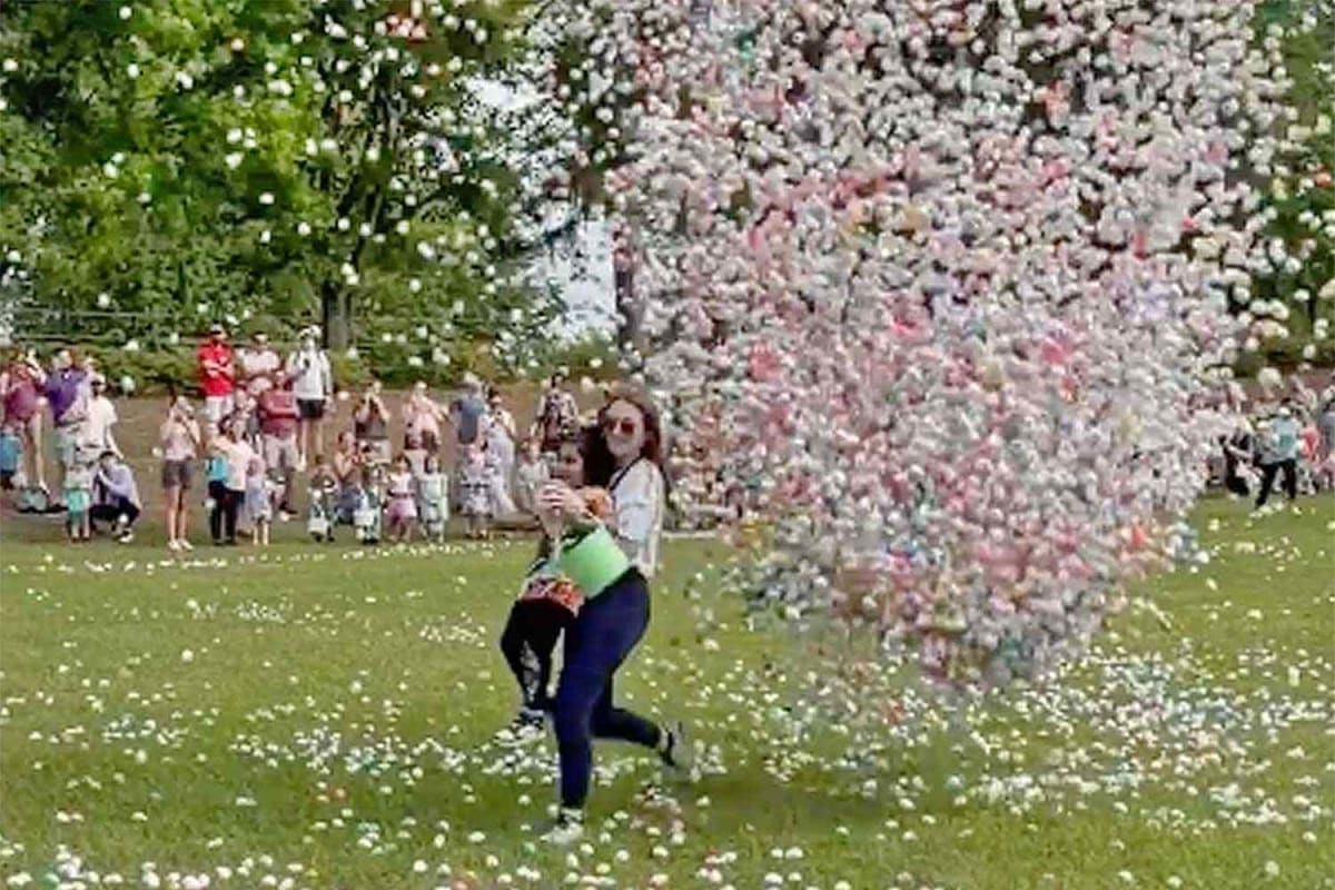 Volunteer running across field to rescue small child before Easter eggs fall from crane