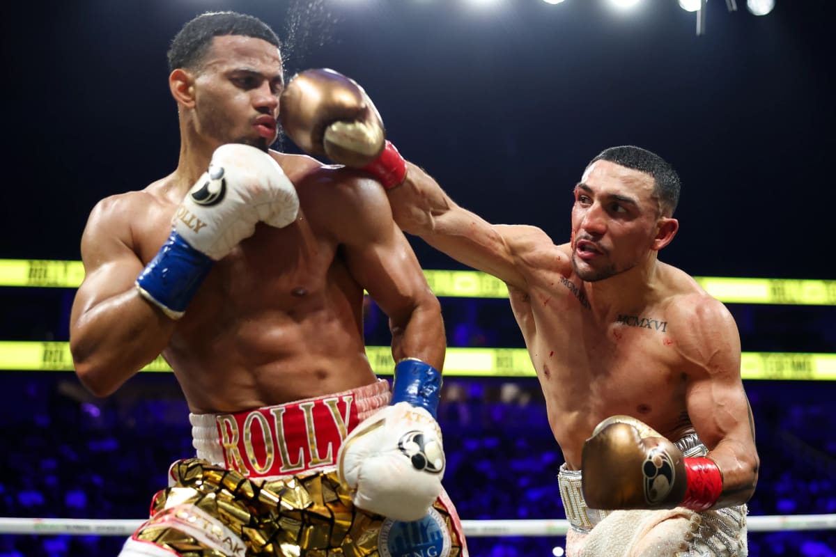 Boxer Teofimo Lopez raising his arms in victory wearing championship belt at Las Vegas arena