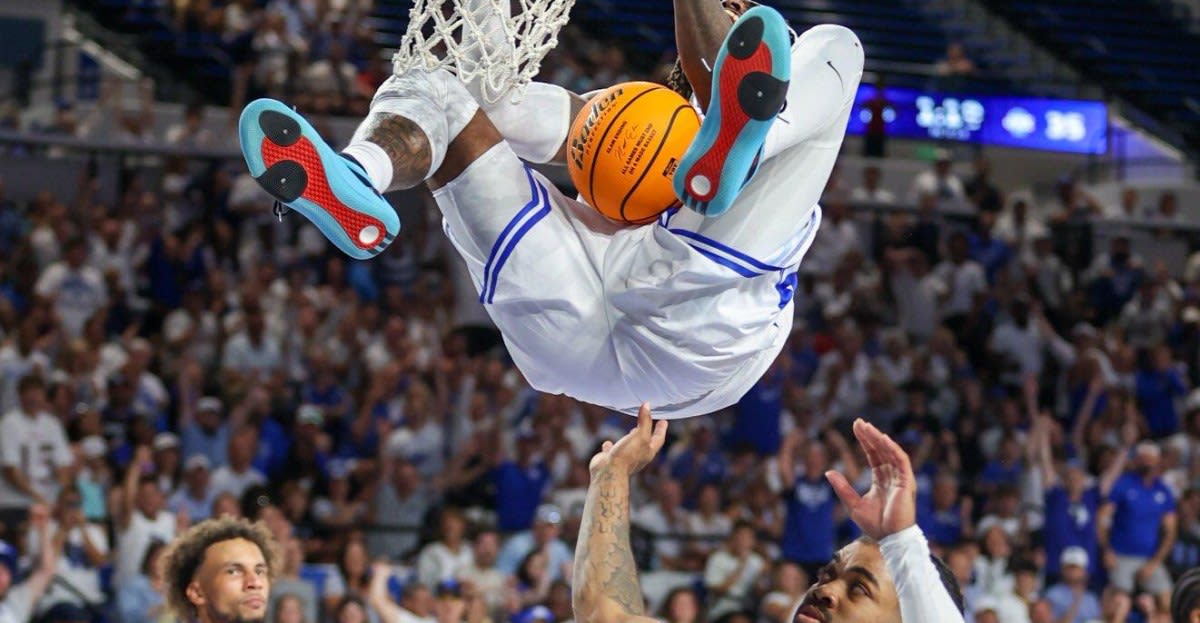 Kentucky alumni basketball players celebrating victory on court with cheering crowd behind them