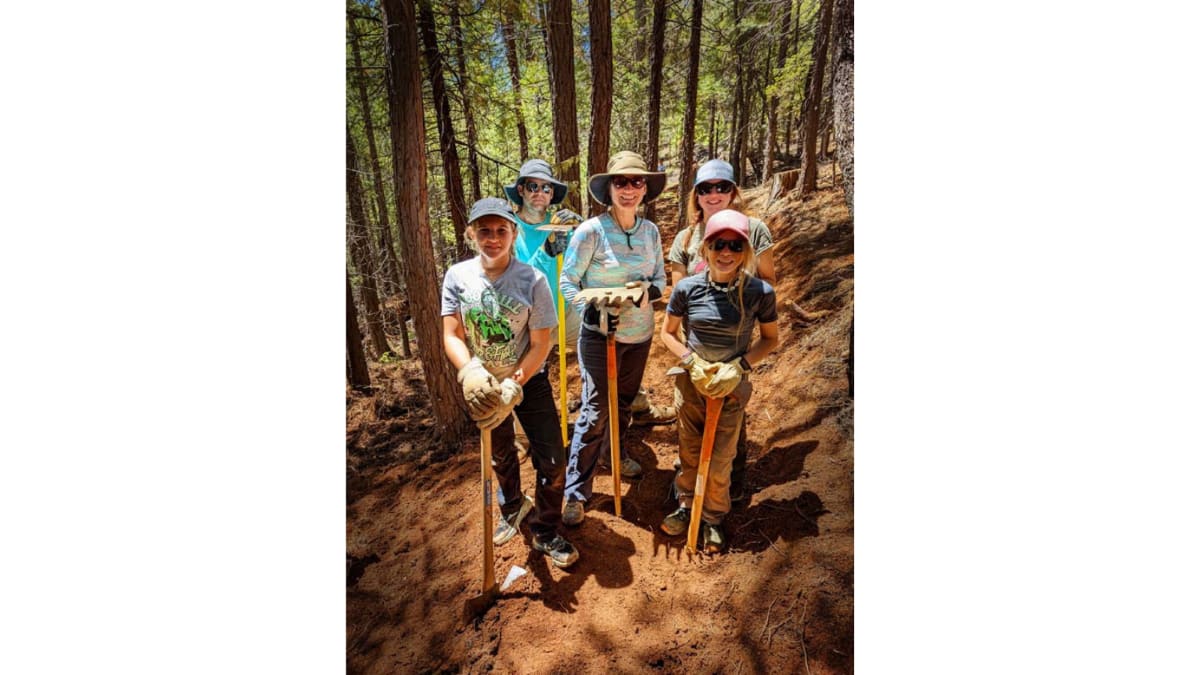 Volunteers working together on mountain trail restoration project in California wilderness