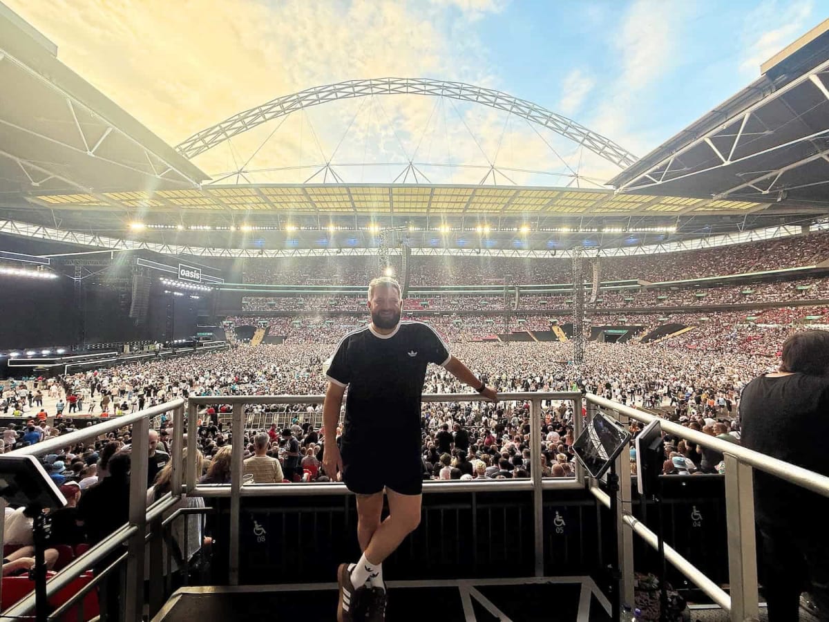 Luke Holdsworth playing air guitar while signing in British Sign Language at Oasis concert