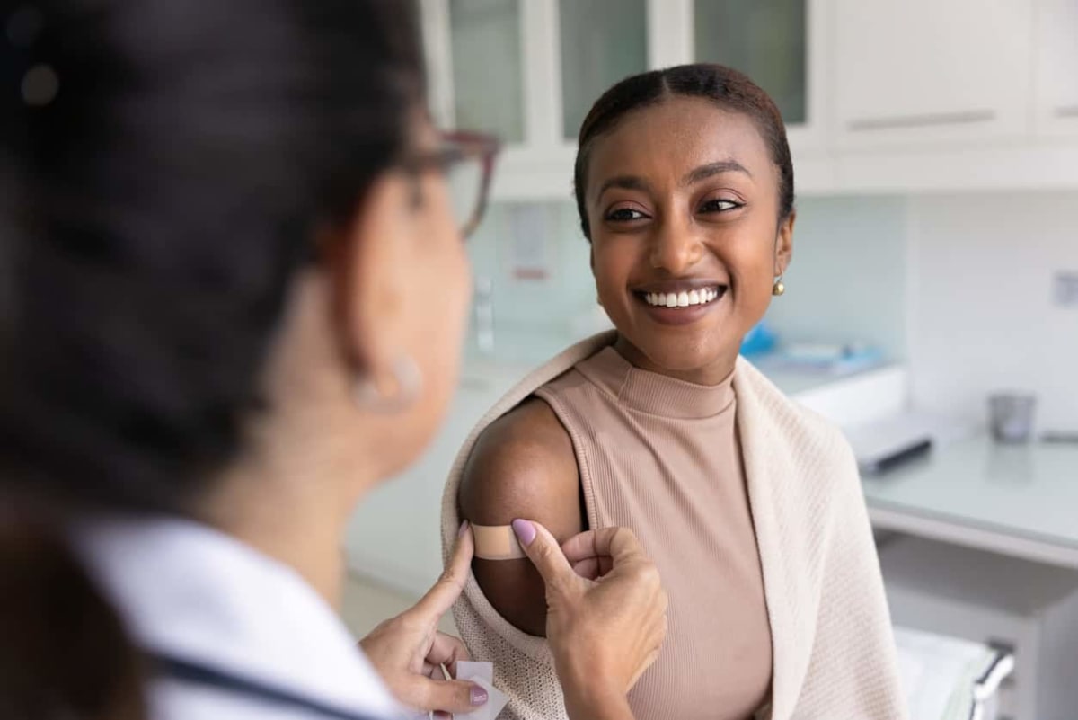 ** Medical researcher examining vaccine vial in laboratory setting with microscope and equipment