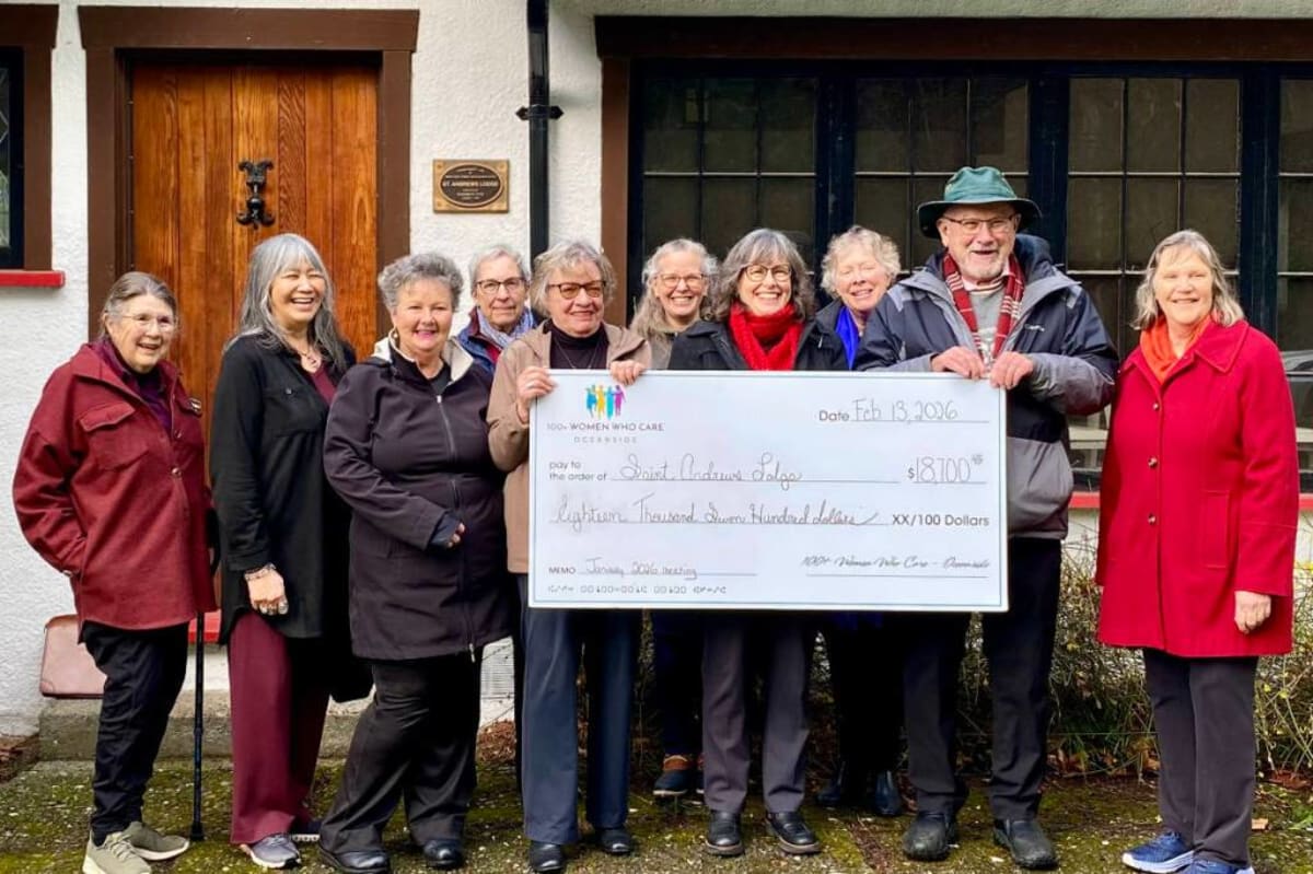 Five women and councillors hold oversized $18,700 check outside historic St. Andrews Lodge in Qualicum Beach