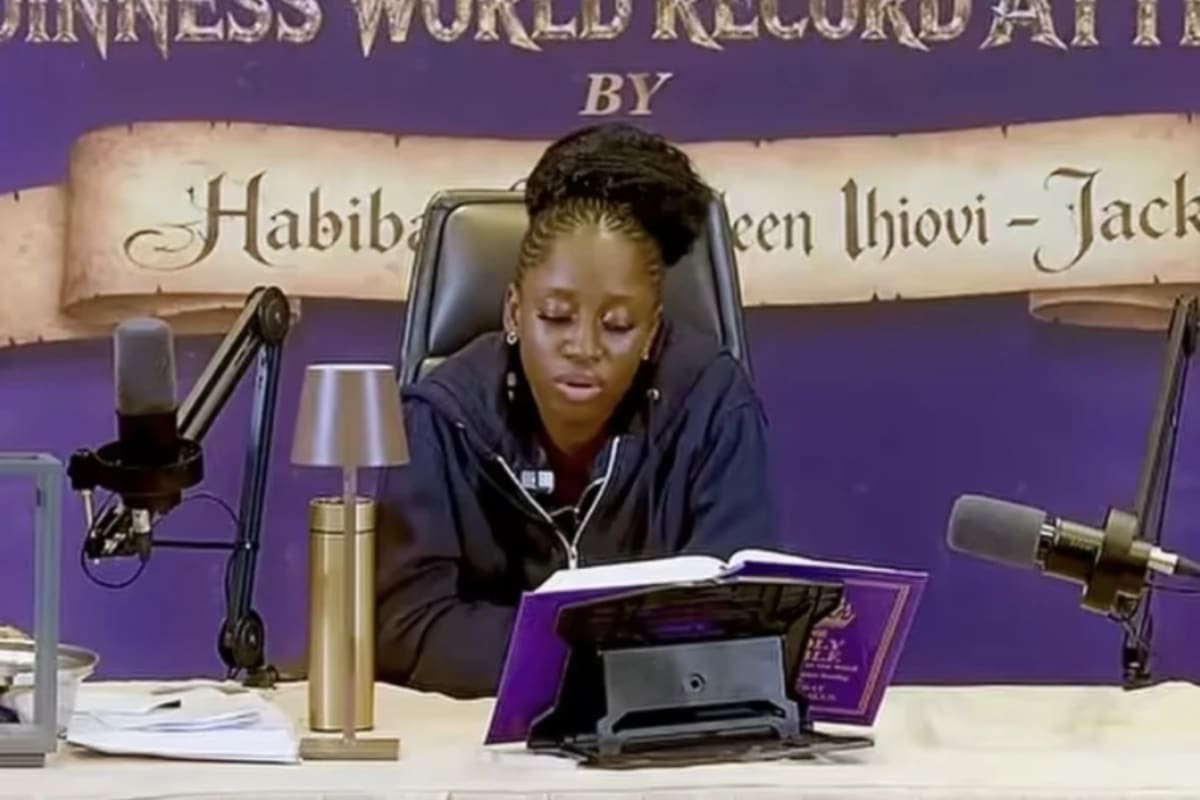 Young Nigerian woman reading Bible aloud at podium during her 144-hour world record attempt