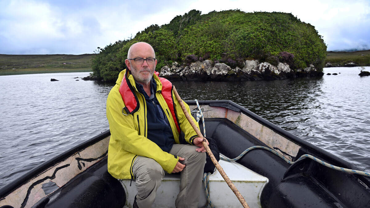 Archaeologist Michael Gibbons examines ancient stone crannóg structure emerging from Lough Fee waters in Connemara Ireland