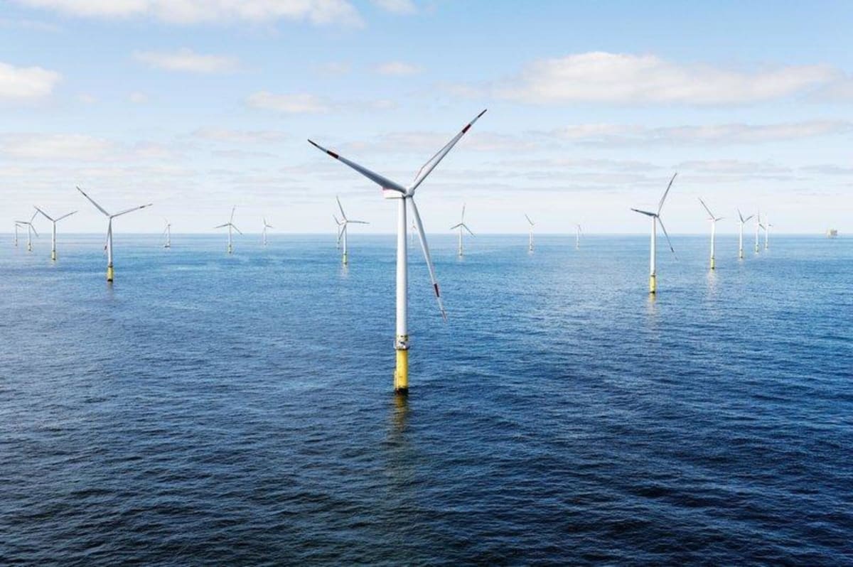 Massive offshore wind turbines spinning above ocean waves generating clean renewable electricity