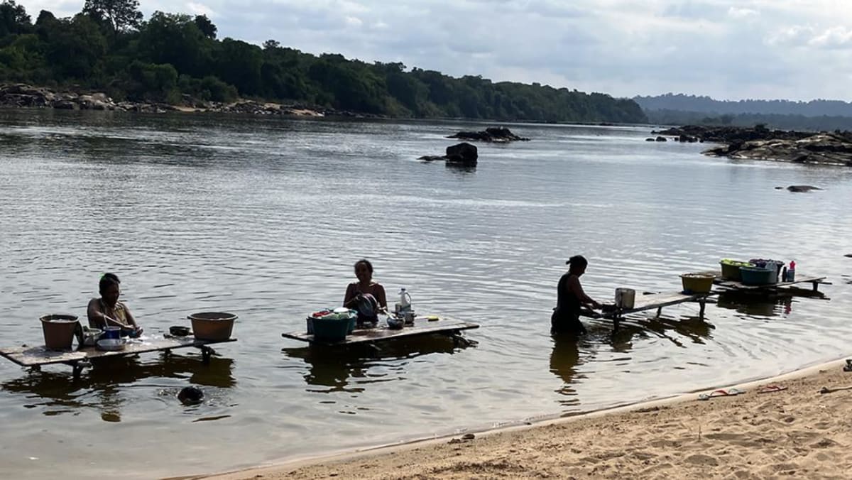 Women washing clothes on wooden platforms along the Iriri River in Brazilian Amazon rainforest community
