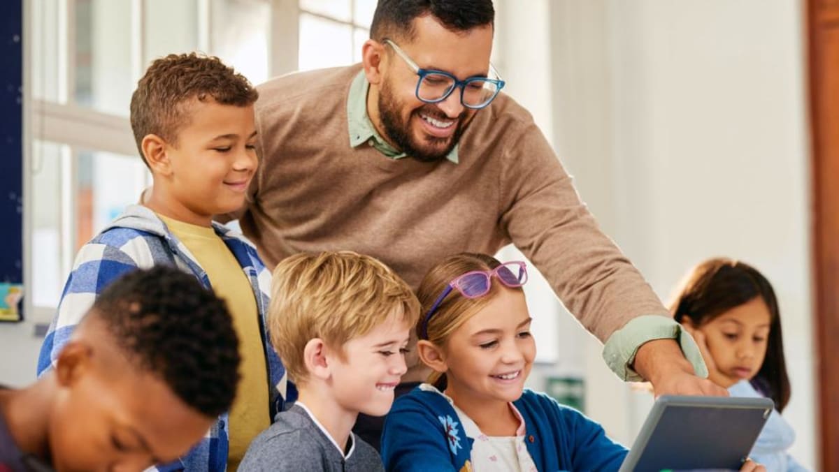 Diverse high school students studying together in supportive, bright classroom environment