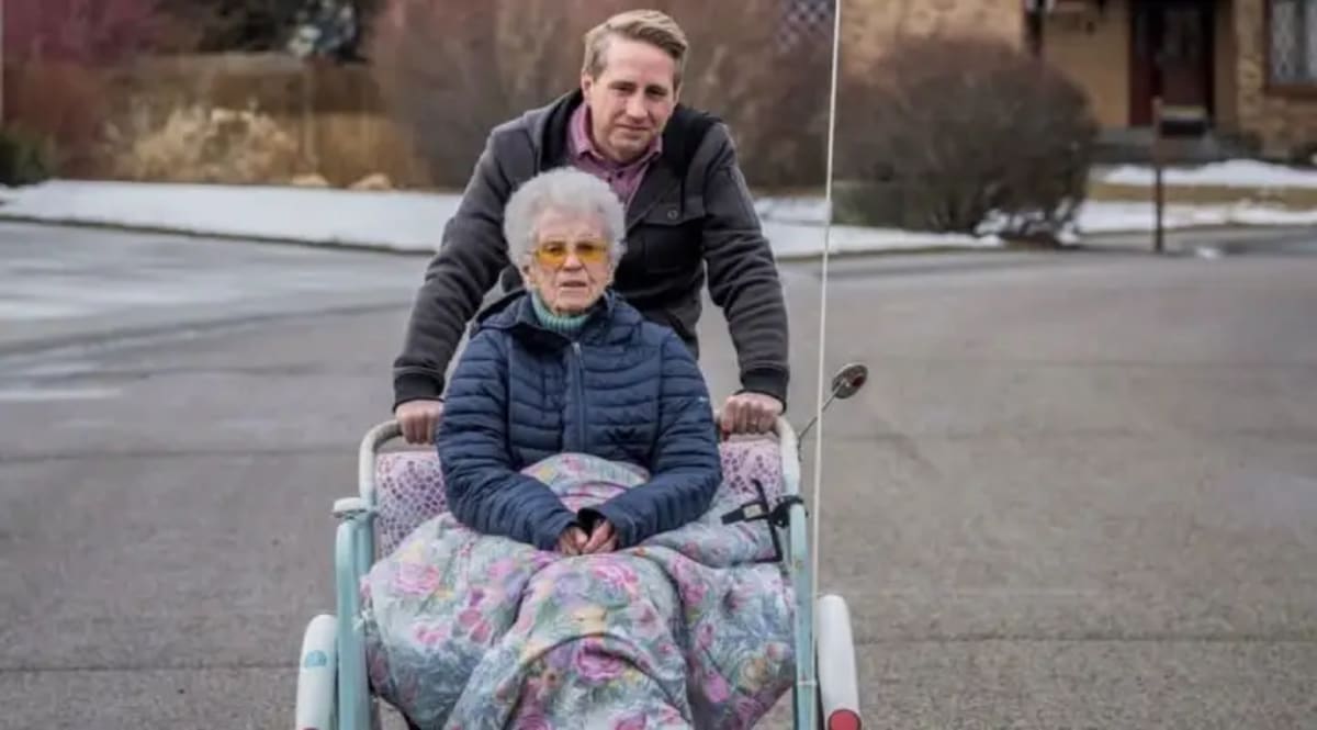 Executive director Joel Freston pedaling elderly woman on orange three-wheeled passenger bike outdoors