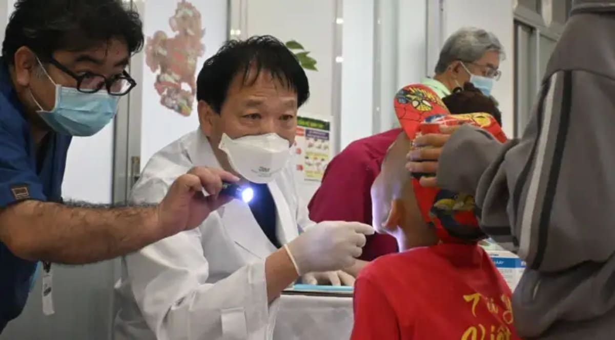 Japanese surgeon examining young Vietnamese child in hospital preparing for cleft palate surgery
