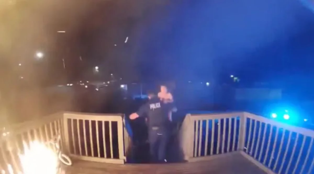 Police officer in uniform standing with rescued mother and two children outside apartment building
