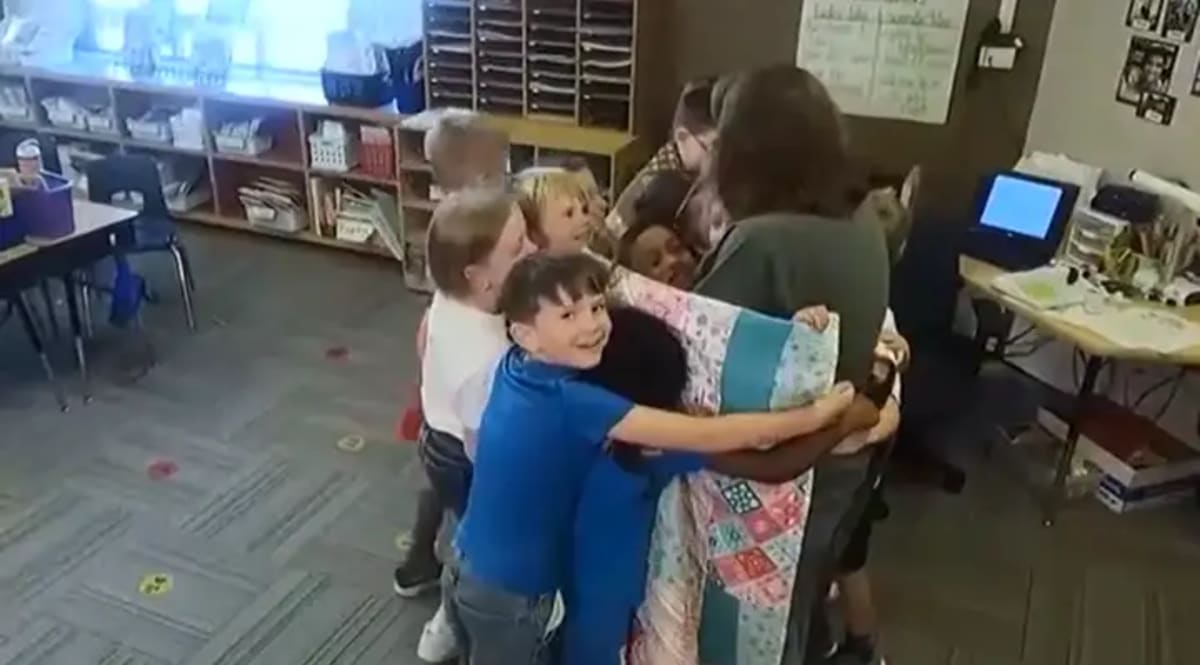 Second-grade teacher Kim Rohlf displaying colorful personalized quilts made for her students
