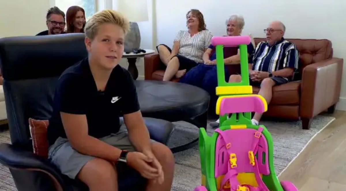 Teenage boy assembles pink 3D-printed wheelchair components designed for toddler with disabilities