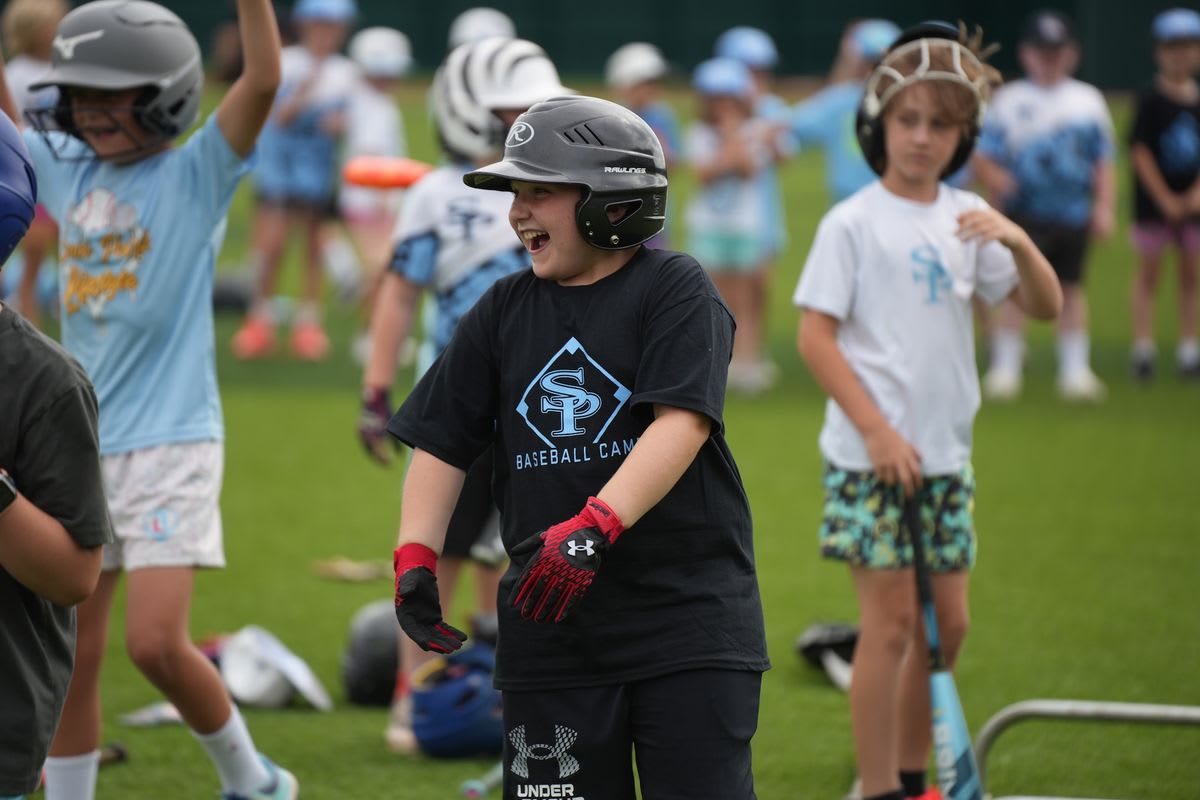 Young baseball campers practice drills with Spain Park High School players on diamond