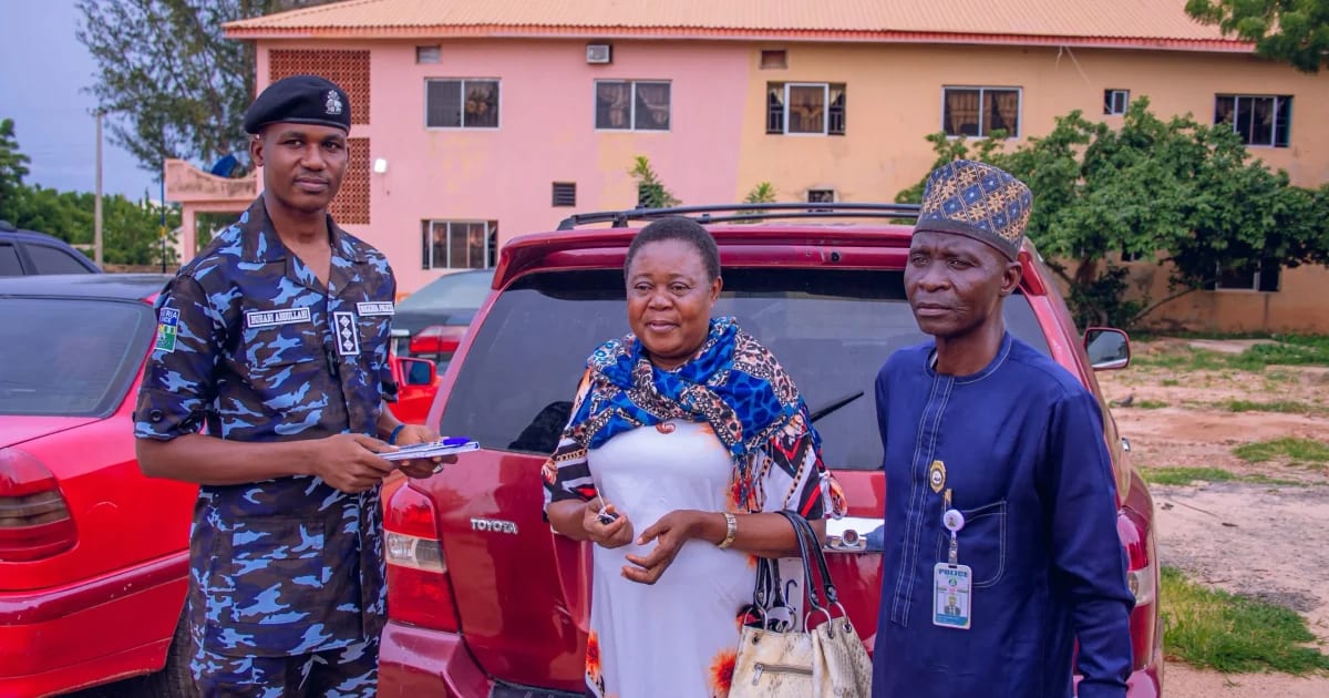 Nigerian police officers hand car keys to woman at vehicle recovery ceremony