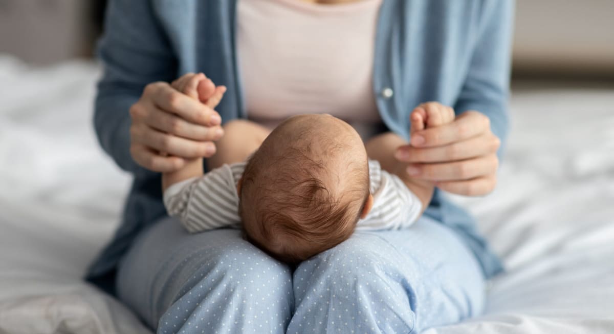Smiling parent holding newborn baby in hospital room, representing families benefiting from paid leave