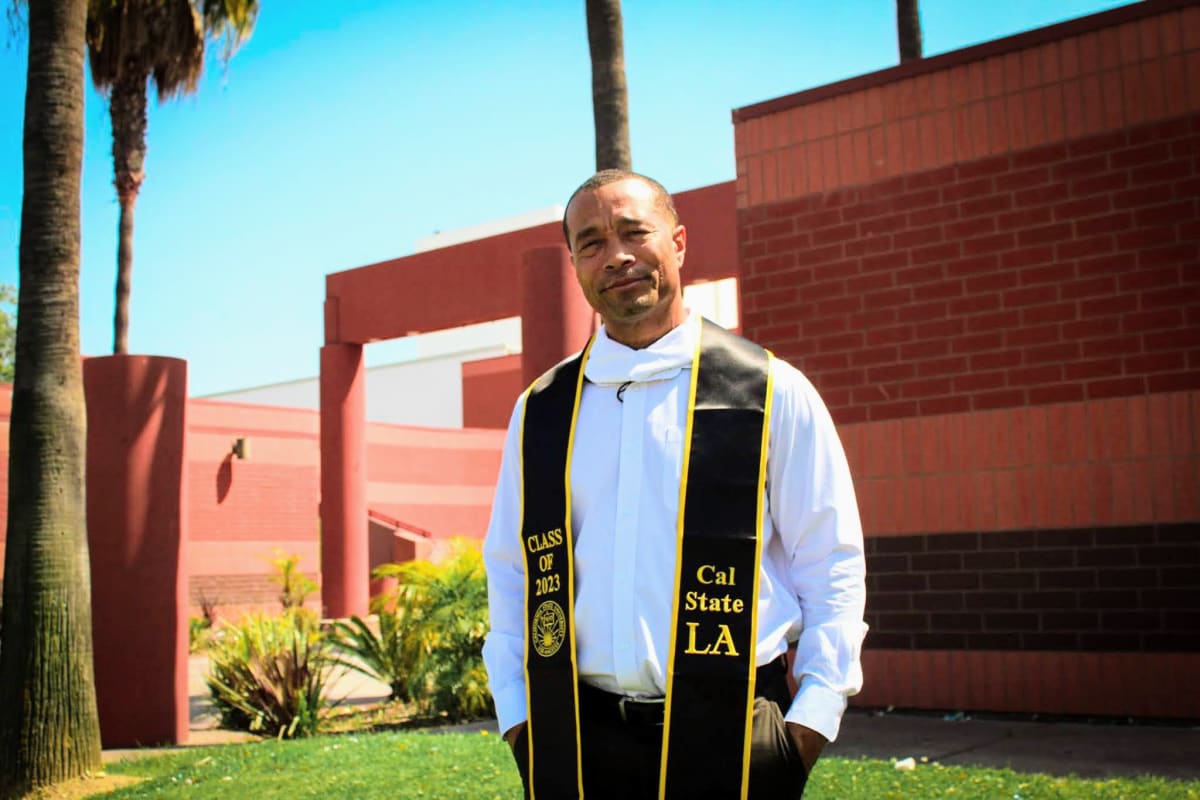 Allen Burnett in graduation regalia walking at ceremony after earning his college degree