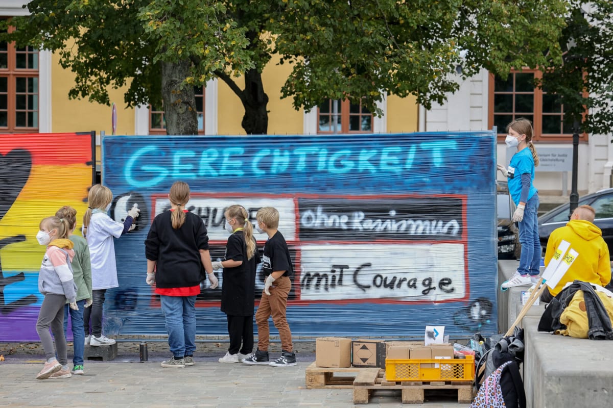 Two students hanging School without Racism banner on brick school building in Germany