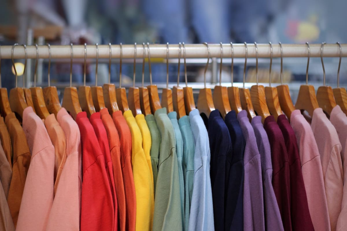 ** Colorful clothing hanging on racks representing sustainable fashion and textile recycling initiatives
