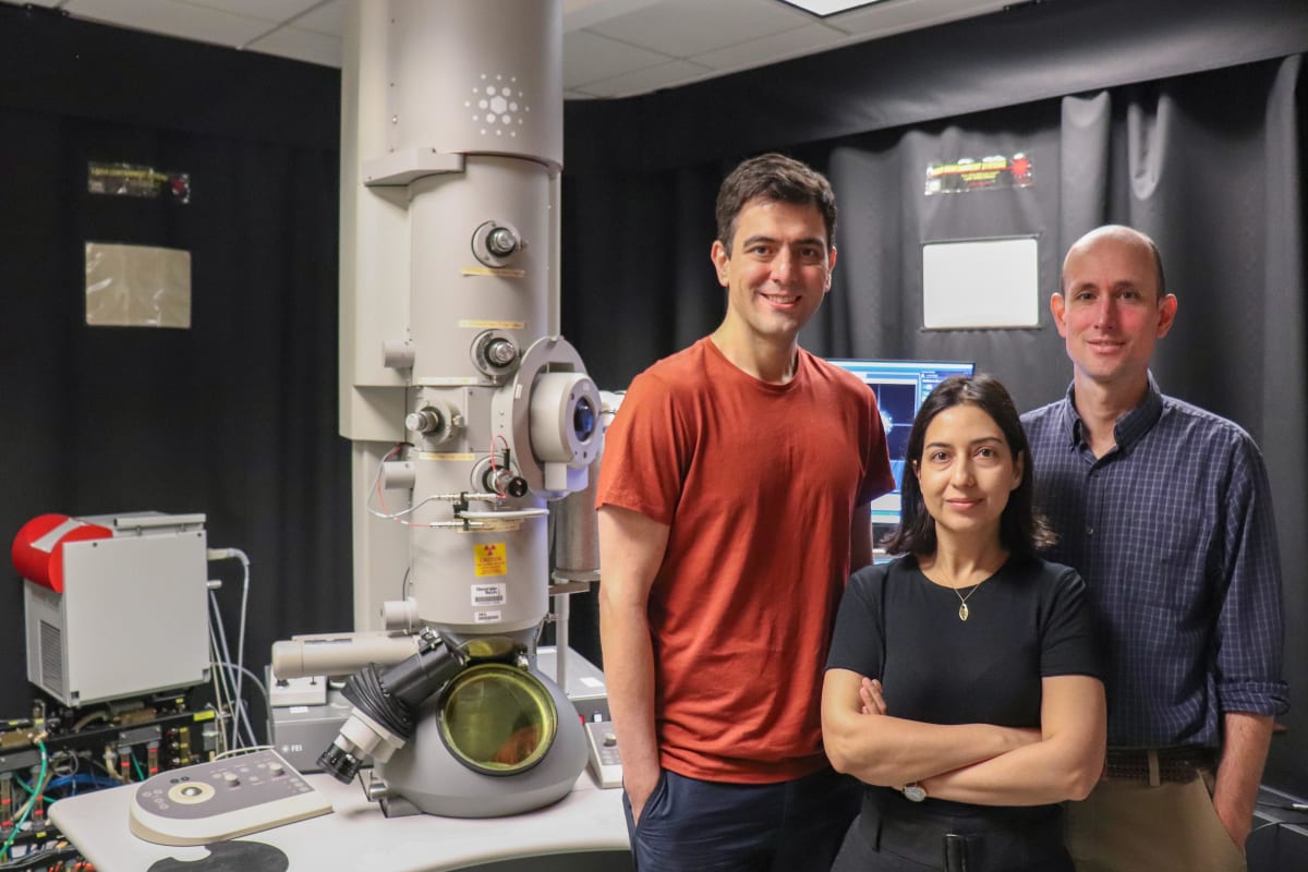 Three Georgia Tech engineering professors standing in front of an electron microscope in their laboratory
