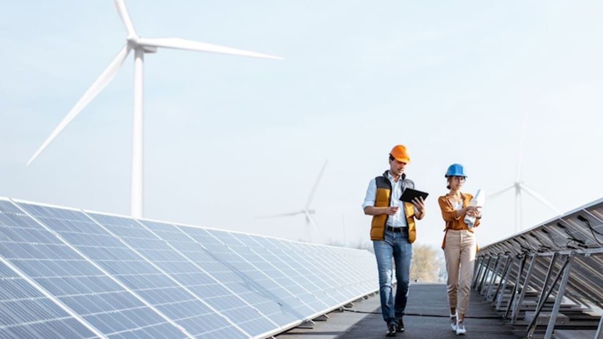 Modern industrial facility with solar panels and wind turbines representing clean energy partnership