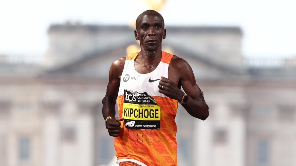 Eliud Kipchoge crossing finish line with arms raised in celebration at marathon