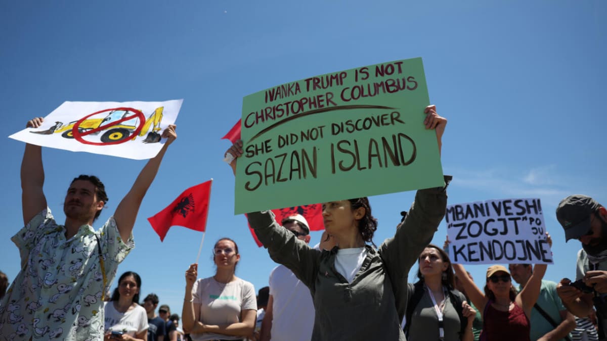 ** Protesters holding inflatable flamingos gather on sandy beach at Albanian coastal nature reserve