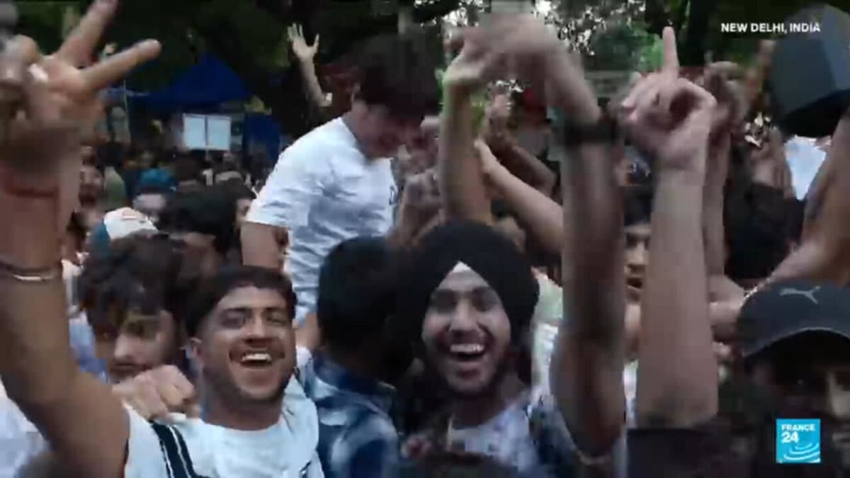Young Indian students celebrating with raised arms at Jantar Mantar protest site in New Delhi