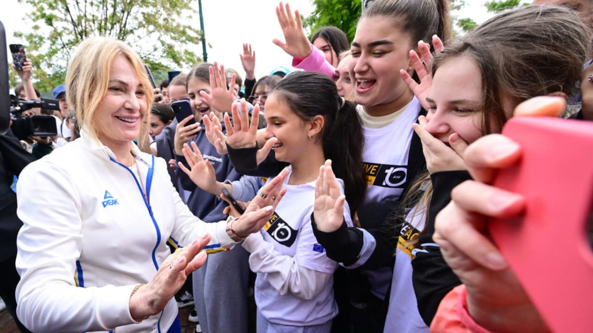 Nadia Comaneci smiling and greeting young gymnasts at her namesake gym in Onesti, Romania